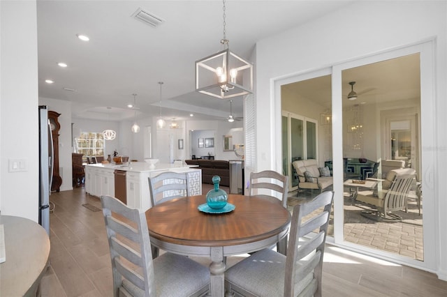 dining area featuring ceiling fan with notable chandelier and light hardwood / wood-style floors