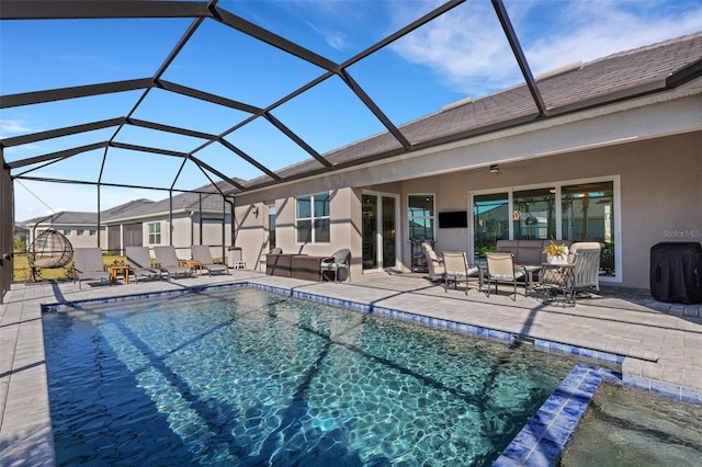 view of swimming pool featuring an outdoor hangout area, glass enclosure, ceiling fan, and a patio area