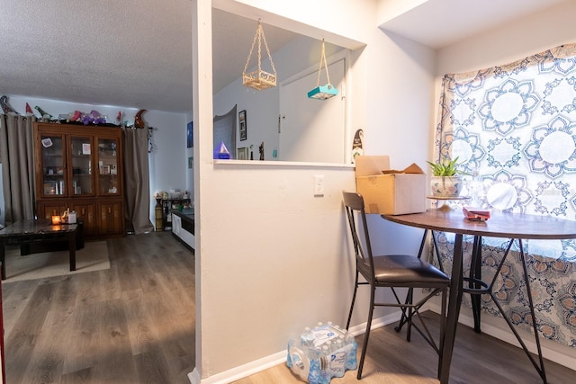 dining space featuring wood-type flooring and a textured ceiling