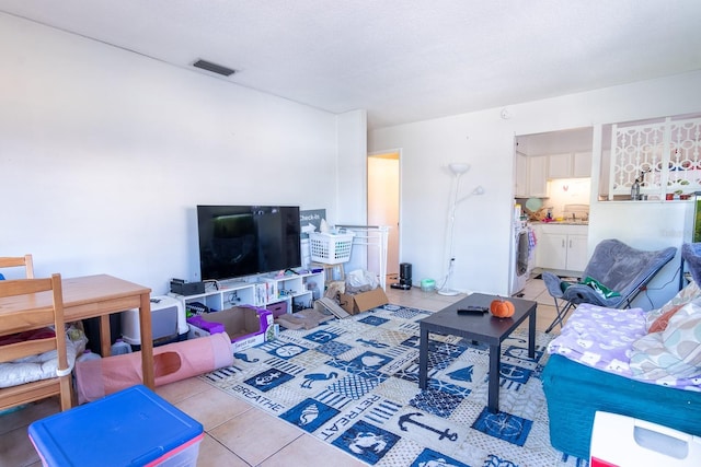 living room featuring light tile patterned floors, a textured ceiling, and washer / dryer