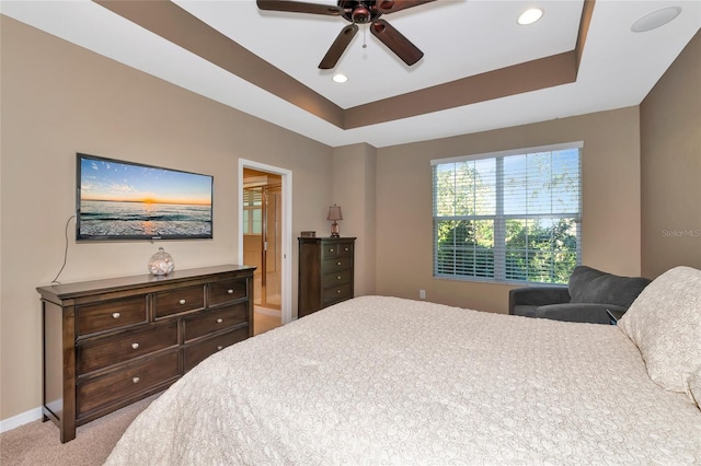 bedroom with ceiling fan, a raised ceiling, and light carpet