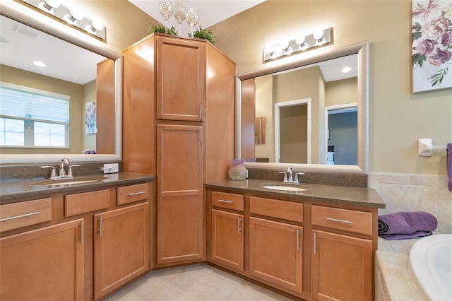 bathroom with tile patterned floors, vanity, and tiled bath