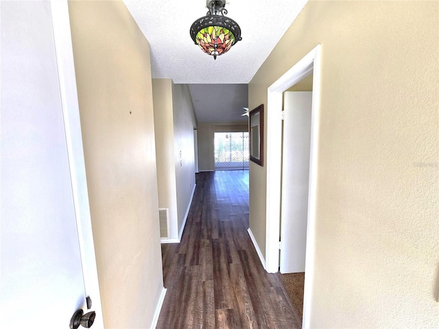 hallway featuring a textured ceiling and dark hardwood / wood-style flooring