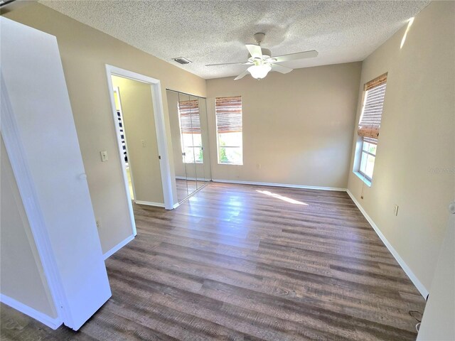 unfurnished room featuring a textured ceiling, ceiling fan, and dark wood-type flooring