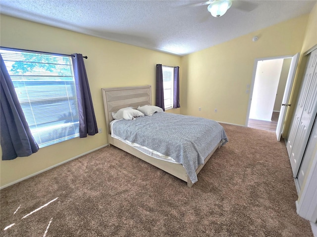 carpeted bedroom with ceiling fan, a closet, and a textured ceiling