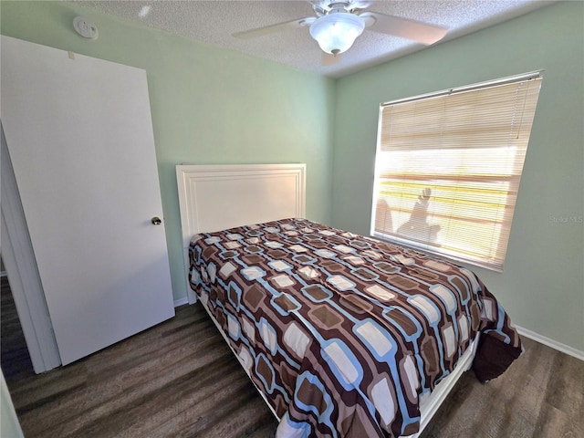 bedroom with a textured ceiling, dark hardwood / wood-style floors, and ceiling fan