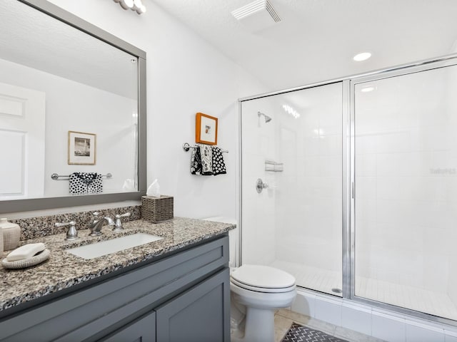 bathroom featuring toilet, vanity, tile patterned floors, and a shower with shower door