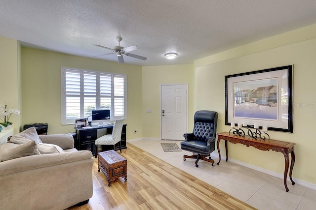 living room with ceiling fan, light hardwood / wood-style floors, and a textured ceiling