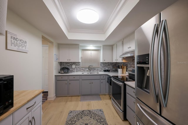 kitchen with appliances with stainless steel finishes, light hardwood / wood-style flooring, ornamental molding, and sink