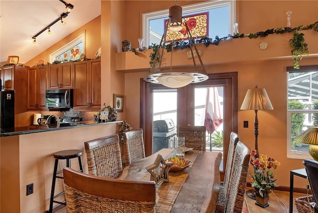 tiled dining area with plenty of natural light, vaulted ceiling, and sink