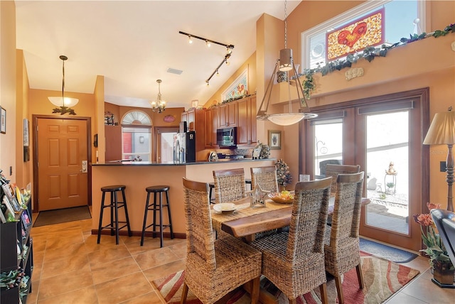 dining area with light tile patterned floors, rail lighting, high vaulted ceiling, and a chandelier