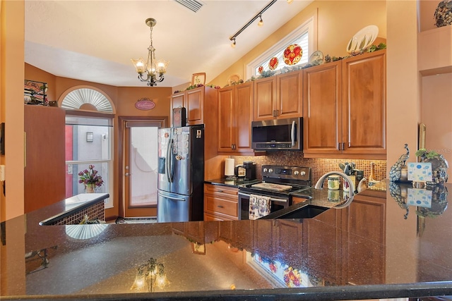 kitchen featuring sink, appliances with stainless steel finishes, tasteful backsplash, a notable chandelier, and kitchen peninsula