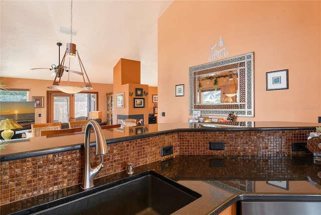 kitchen with tasteful backsplash, high vaulted ceiling, hanging light fixtures, and sink