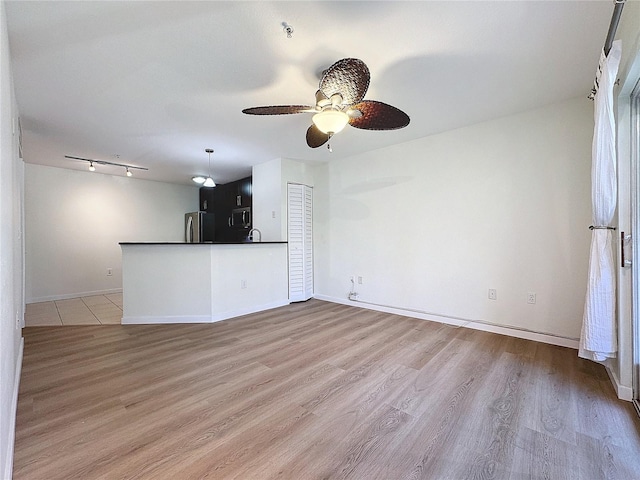 unfurnished living room featuring ceiling fan and light hardwood / wood-style flooring