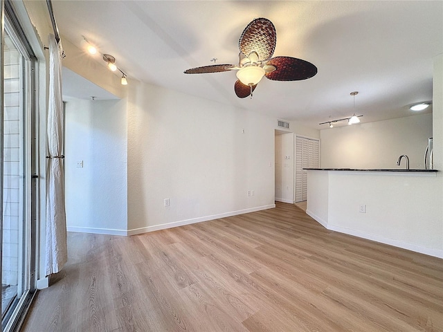 unfurnished living room with light hardwood / wood-style floors, ceiling fan, and sink