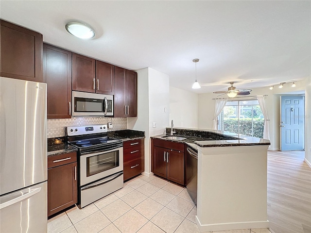 kitchen featuring kitchen peninsula, sink, dark stone countertops, and appliances with stainless steel finishes