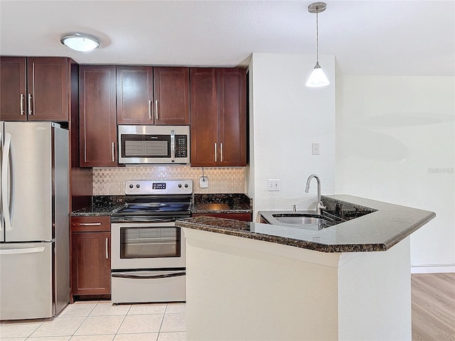 kitchen with sink, light tile patterned floors, tasteful backsplash, decorative light fixtures, and stainless steel appliances