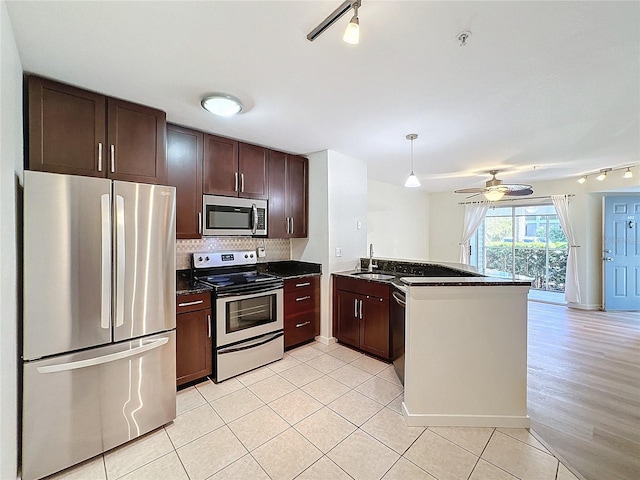 kitchen with kitchen peninsula, appliances with stainless steel finishes, track lighting, ceiling fan, and sink