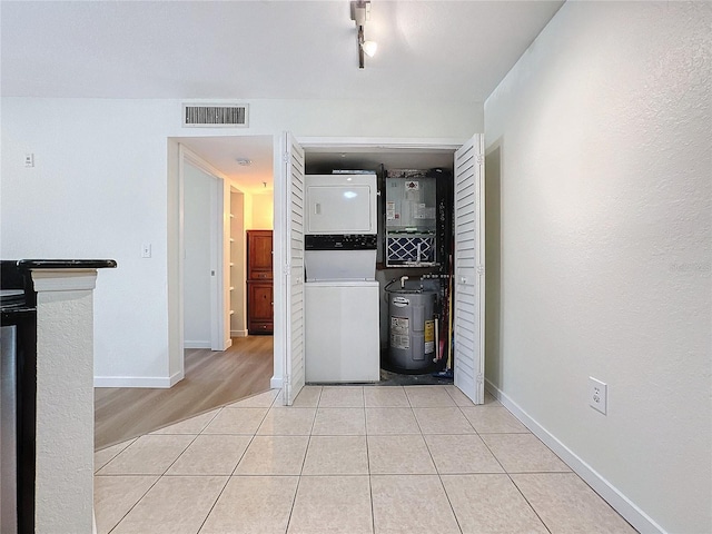 interior space featuring electric water heater, stacked washer and dryer, and light wood-type flooring