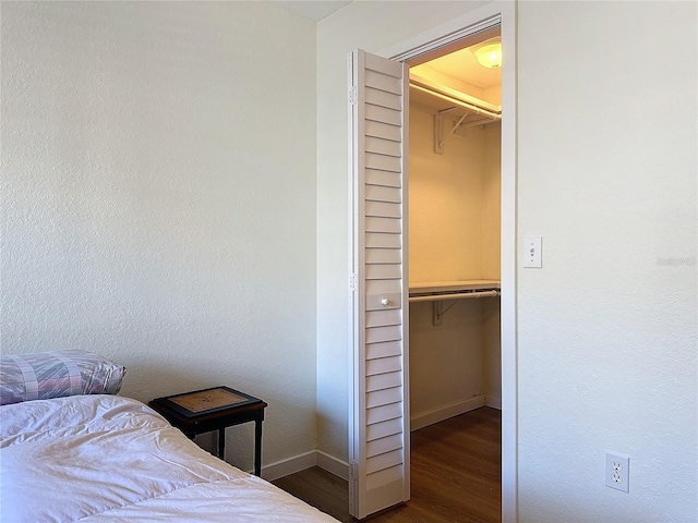 bedroom with a walk in closet, a closet, and dark hardwood / wood-style floors