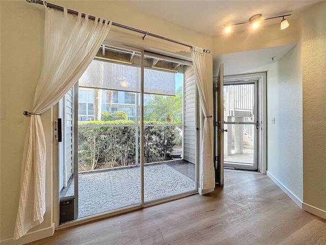 doorway with hardwood / wood-style floors and rail lighting