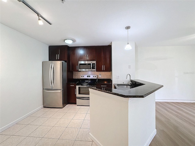 kitchen with decorative backsplash, appliances with stainless steel finishes, sink, hanging light fixtures, and light tile patterned flooring