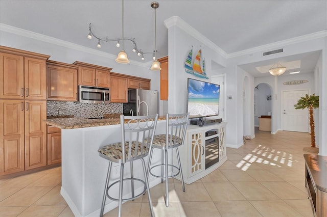500 San Lino Cir Unit 511, Venice, FL 34292 - kitchen with stainless steel appliances, crown molding, light tile patterned floors, backsplash, and brown cabinets