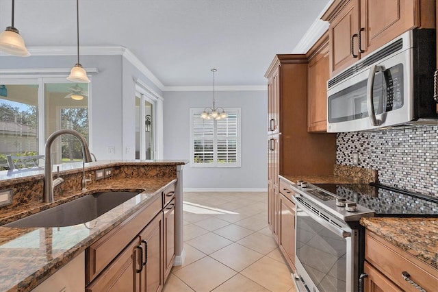 kitchen featuring stainless steel appliances, sink, decorative light fixtures, a notable chandelier, and dark stone countertops