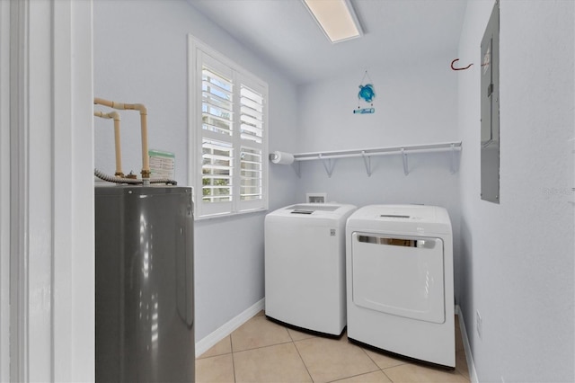 laundry room featuring electric water heater, washer and clothes dryer, and light tile patterned flooring