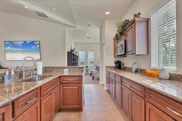 kitchen with light stone countertops, vaulted ceiling, light tile patterned flooring, and sink