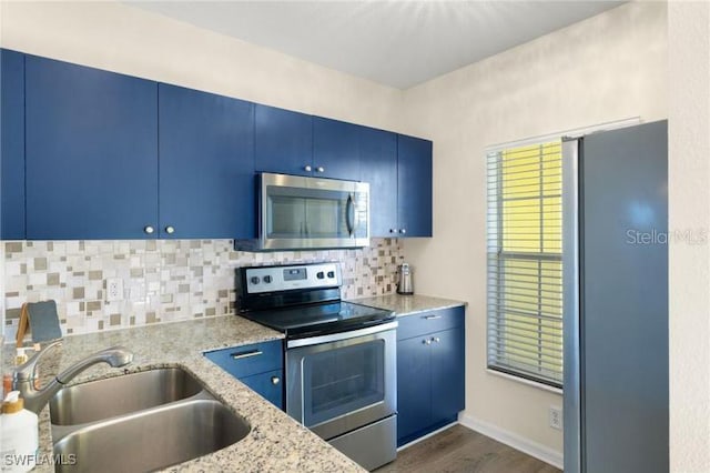 kitchen featuring blue cabinetry, sink, light stone counters, dark hardwood / wood-style flooring, and appliances with stainless steel finishes