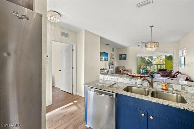 kitchen with light stone counters, sink, blue cabinetry, dishwasher, and light hardwood / wood-style floors