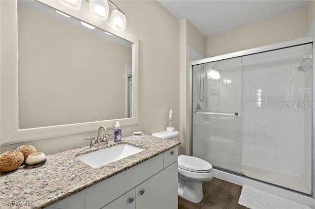 bathroom featuring hardwood / wood-style floors, toilet, an enclosed shower, and vanity