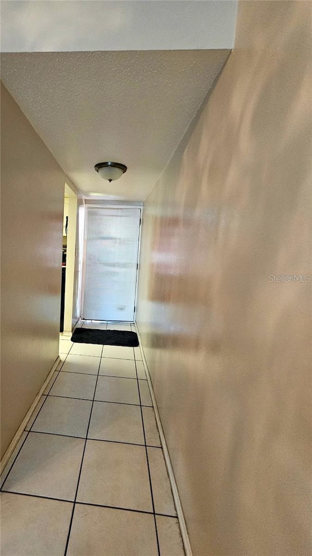 hallway with light tile patterned floors and a textured ceiling