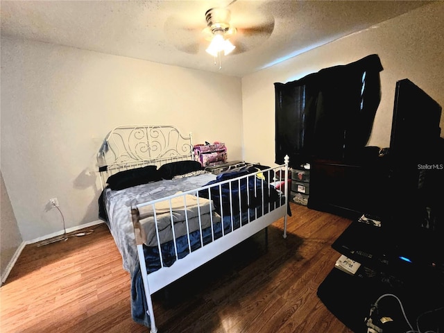 bedroom featuring hardwood / wood-style flooring, ceiling fan, and a textured ceiling