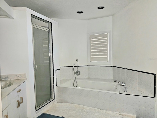 bathroom with a textured ceiling, vanity, and separate shower and tub