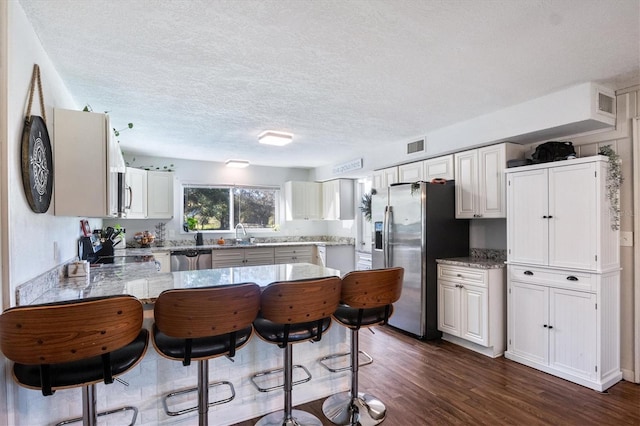 kitchen featuring a textured ceiling, white cabinets, dark hardwood / wood-style floors, and appliances with stainless steel finishes