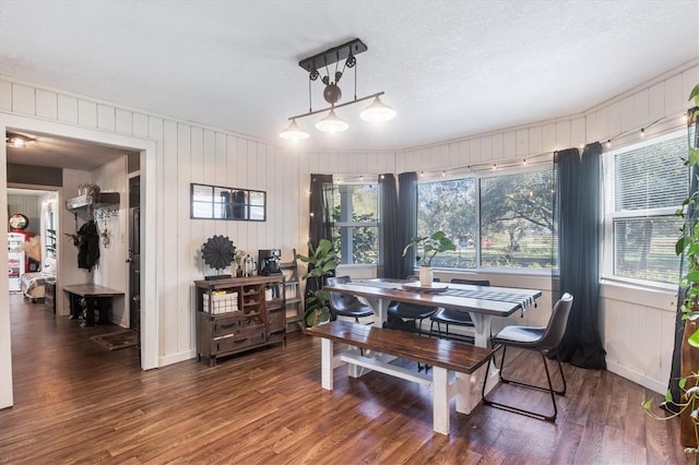 dining space with wooden walls, dark hardwood / wood-style flooring, and a textured ceiling