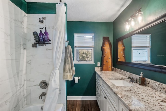 bathroom with hardwood / wood-style floors, vanity, shower / bath combination with curtain, and a textured ceiling