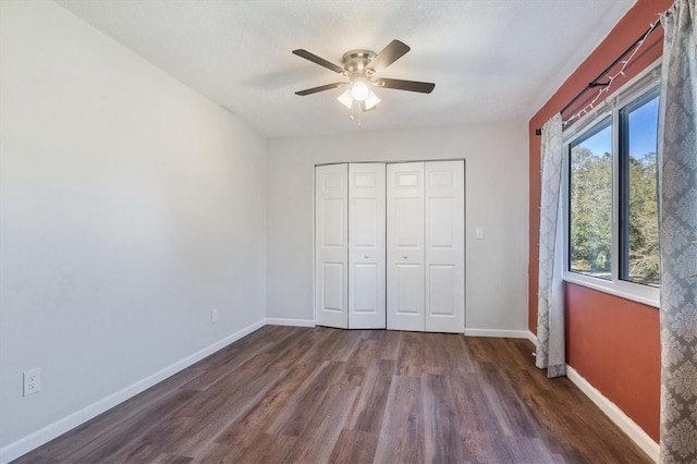 unfurnished bedroom with ceiling fan, dark wood-type flooring, and a closet