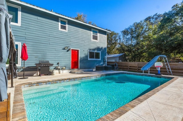 view of swimming pool with a grill, a water slide, and a patio