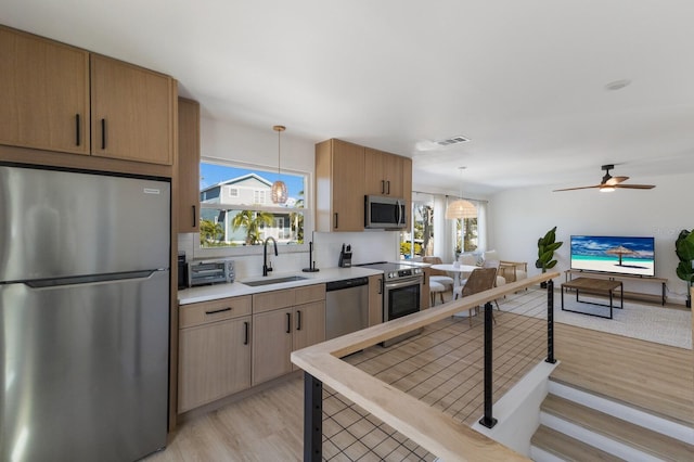 kitchen featuring plenty of natural light, sink, stainless steel appliances, and hanging light fixtures