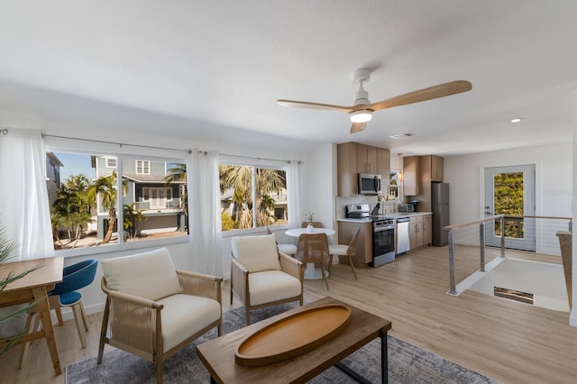 living room with ceiling fan and light hardwood / wood-style flooring