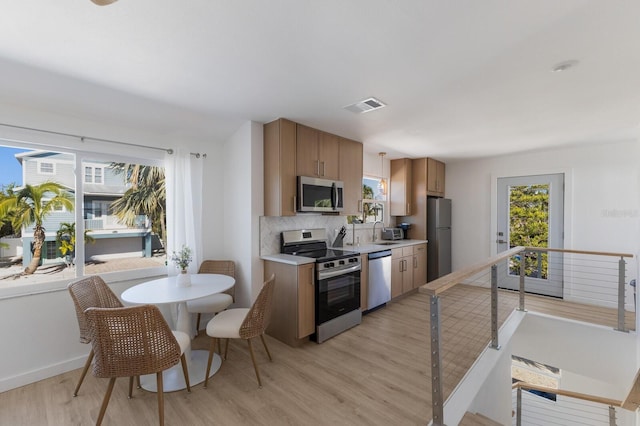 kitchen featuring decorative backsplash, sink, appliances with stainless steel finishes, and light hardwood / wood-style flooring