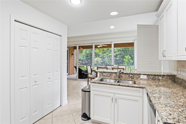 kitchen with white cabinets, light stone countertops, sink, and light tile patterned floors