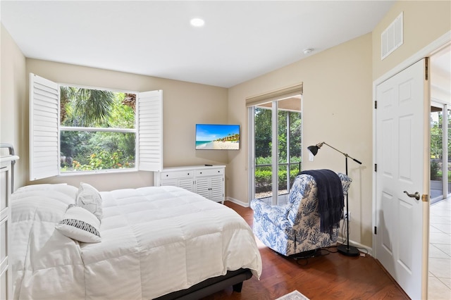 bedroom with access to outside, multiple windows, and hardwood / wood-style floors