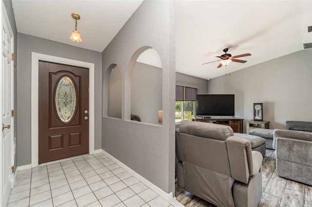 tiled entryway with ceiling fan and lofted ceiling