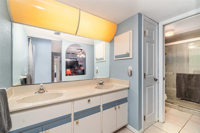 bathroom featuring ceiling fan, tile patterned flooring, a textured ceiling, toilet, and vanity