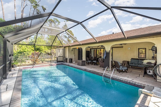 view of swimming pool with an outdoor living space, ceiling fan, a patio area, and glass enclosure