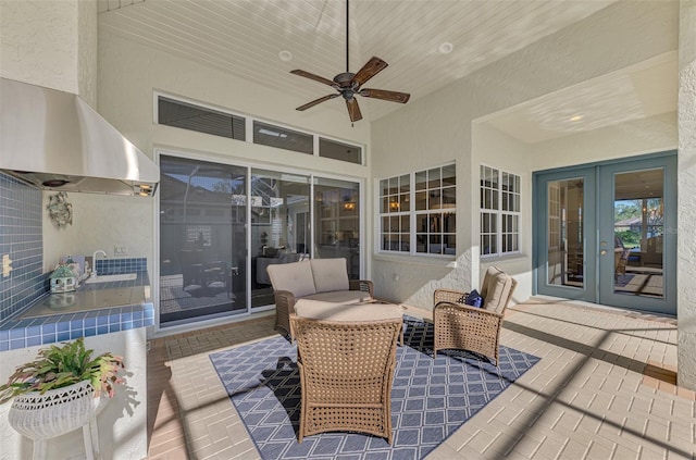 deck with ceiling fan, a patio area, and french doors